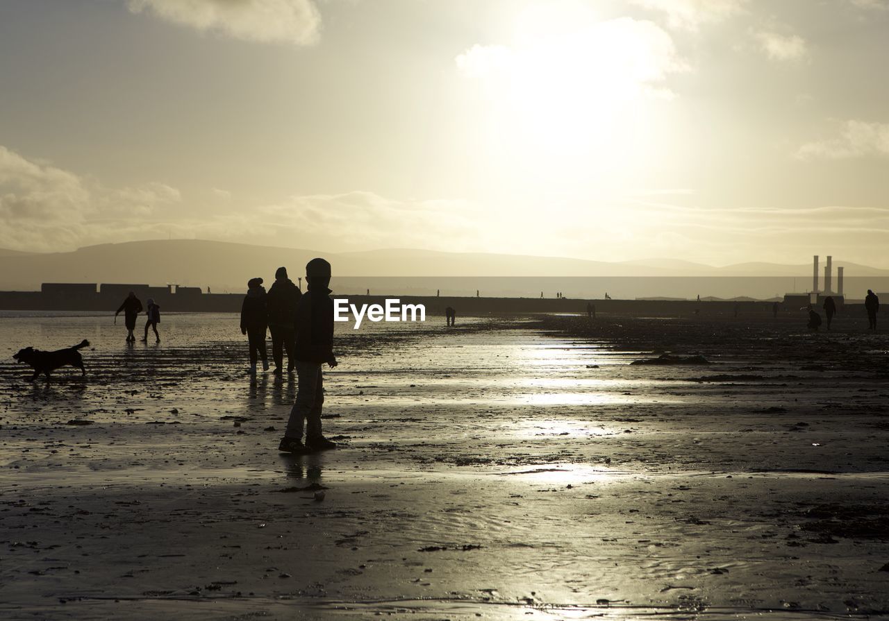 SILHOUETTE MEN ON BEACH AGAINST SKY