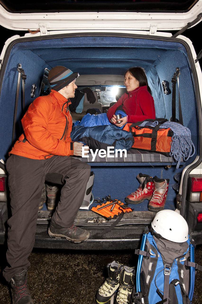 Couple enjoying a hot drink in the back of their camper van