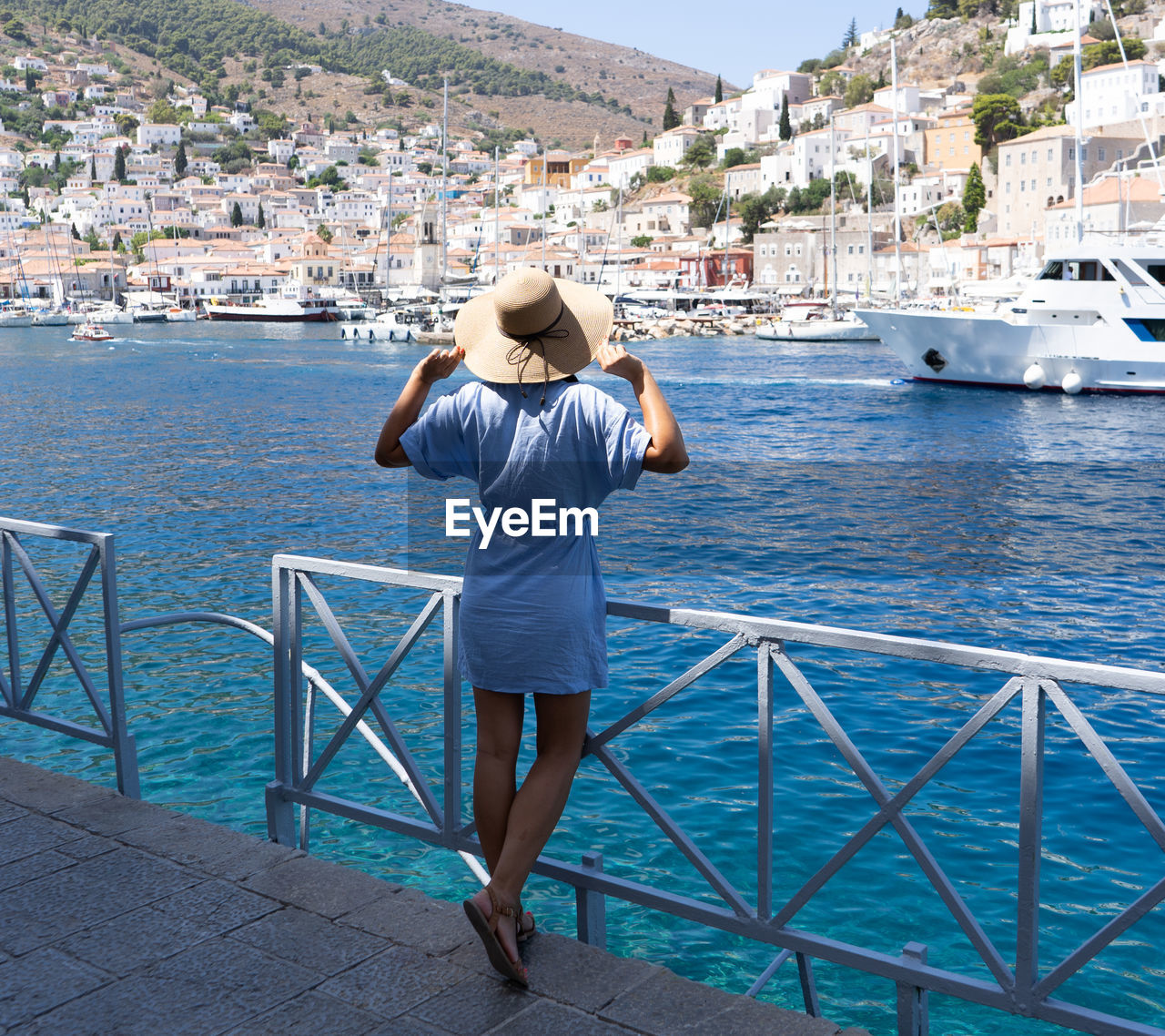 REAR VIEW OF MAN LOOKING AT SEA AGAINST BUILDINGS