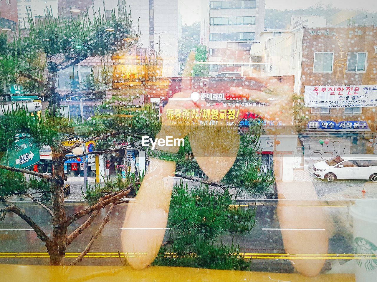 Photographing woman seen through glass with reflection of city