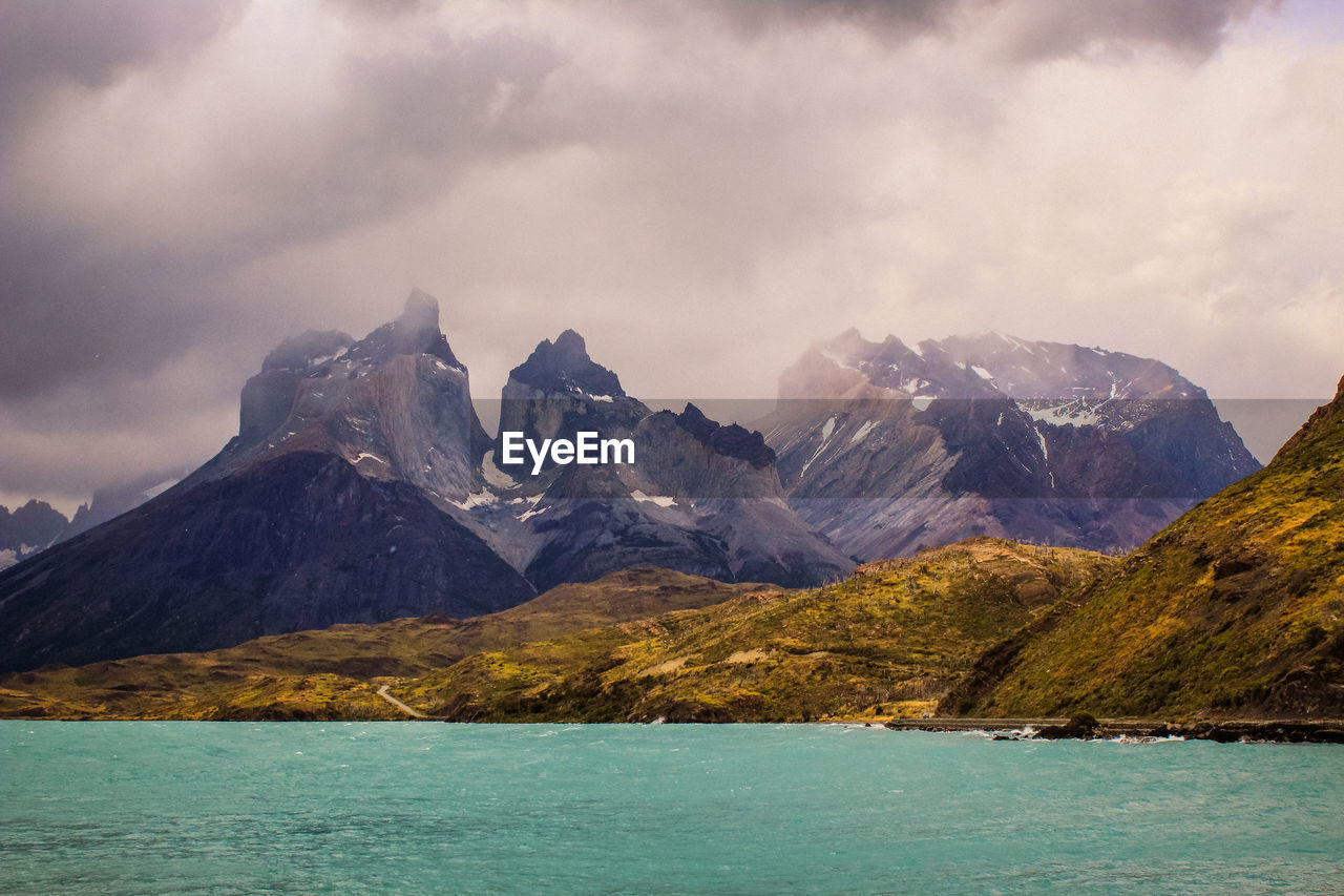 Scenic view of mountains and sea against cloudy sky