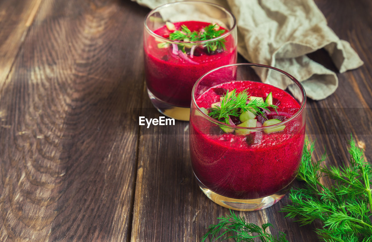 Beetroot gazpacho soup with cucumber and dill in glasses on rustic wooden background