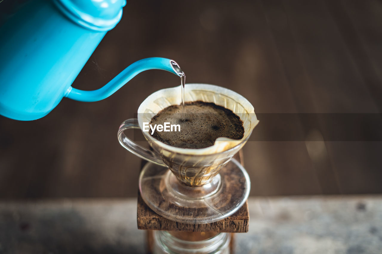 Black coffee pouring in jar on table