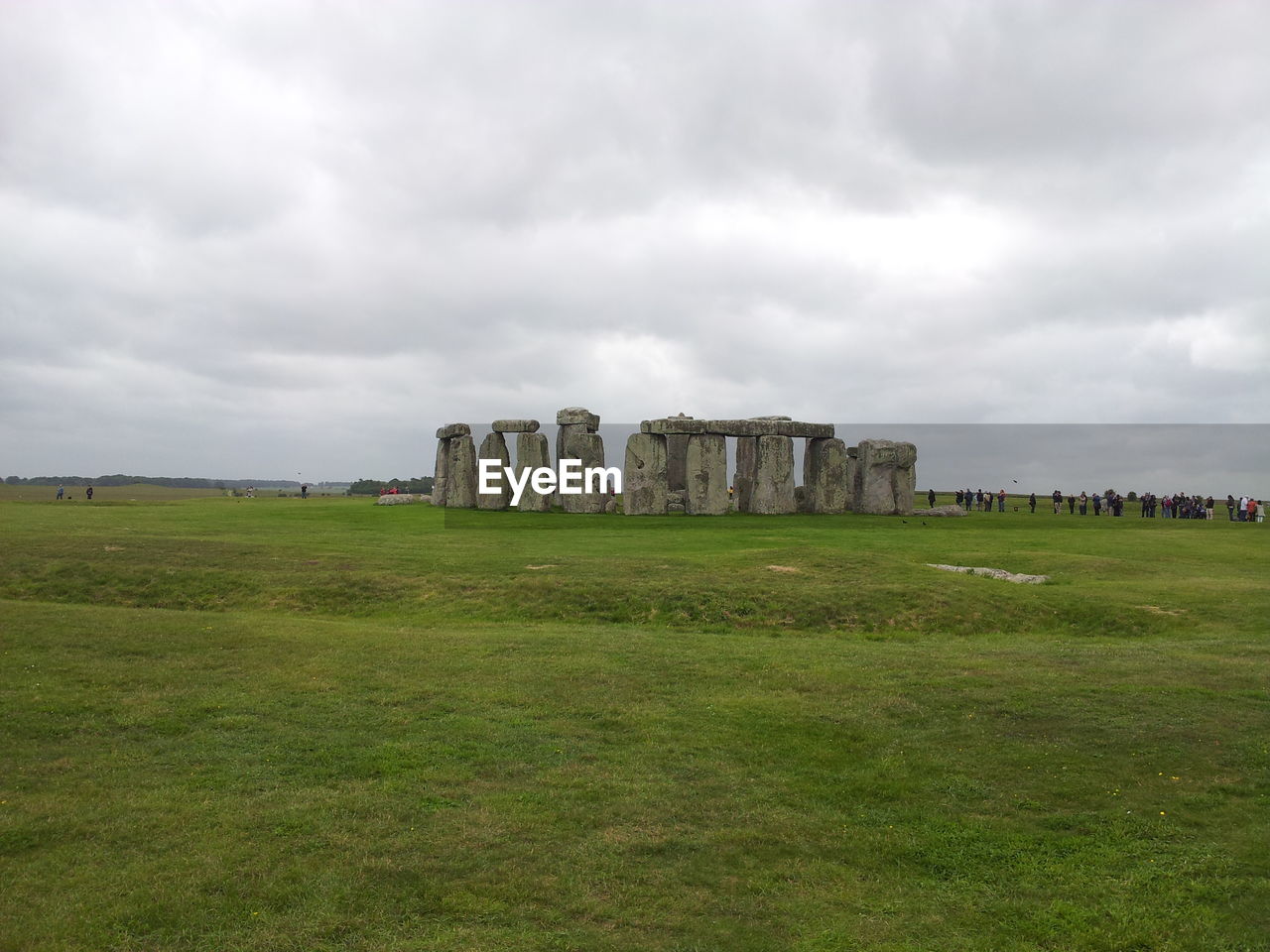 Old ruins on grassy field against cloudy sky