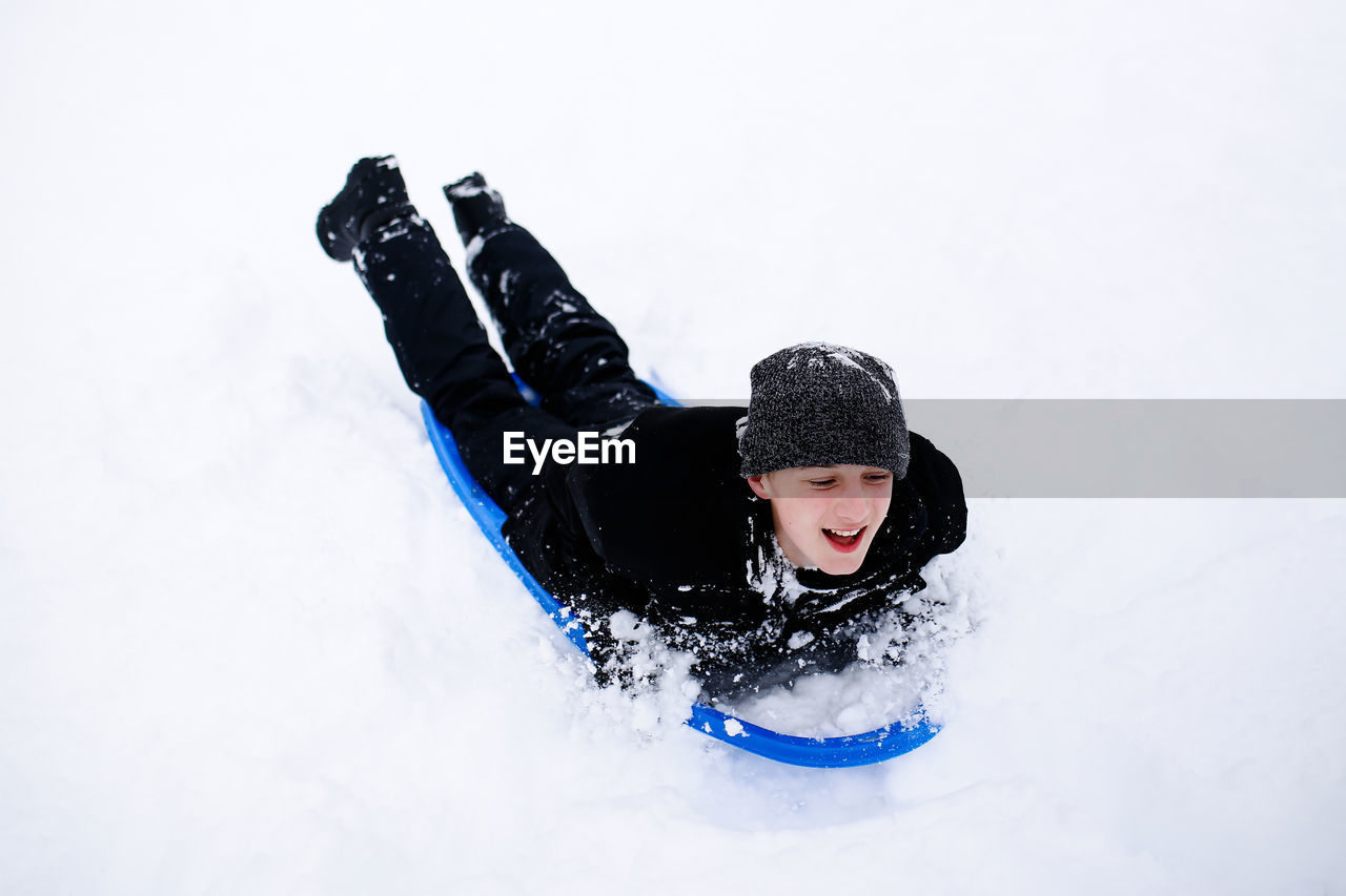 Full length of boy tobogganing on snow