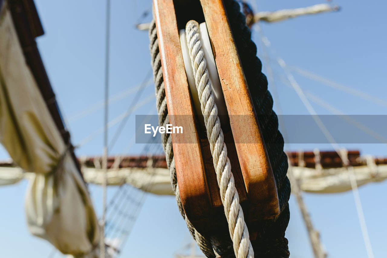 CLOSE-UP OF ROPE TIED TO WOODEN POST AT SHORE