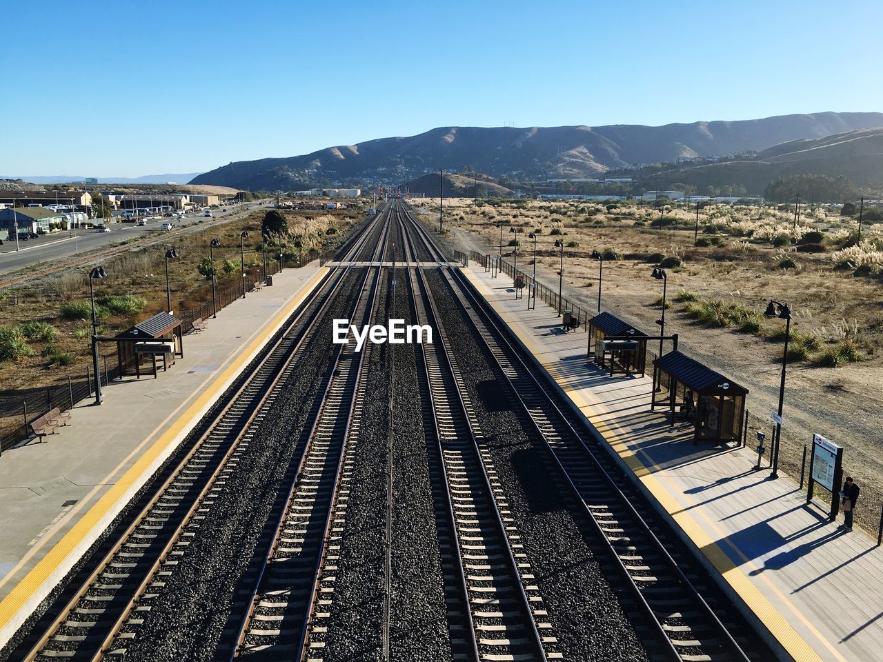 High angle view of railroad tracks and station by field against sky