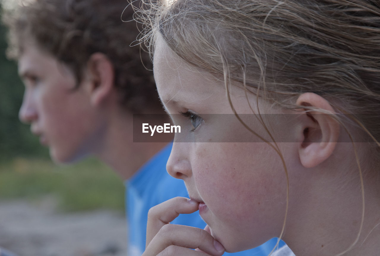 Close-up of siblings looking away outdoors