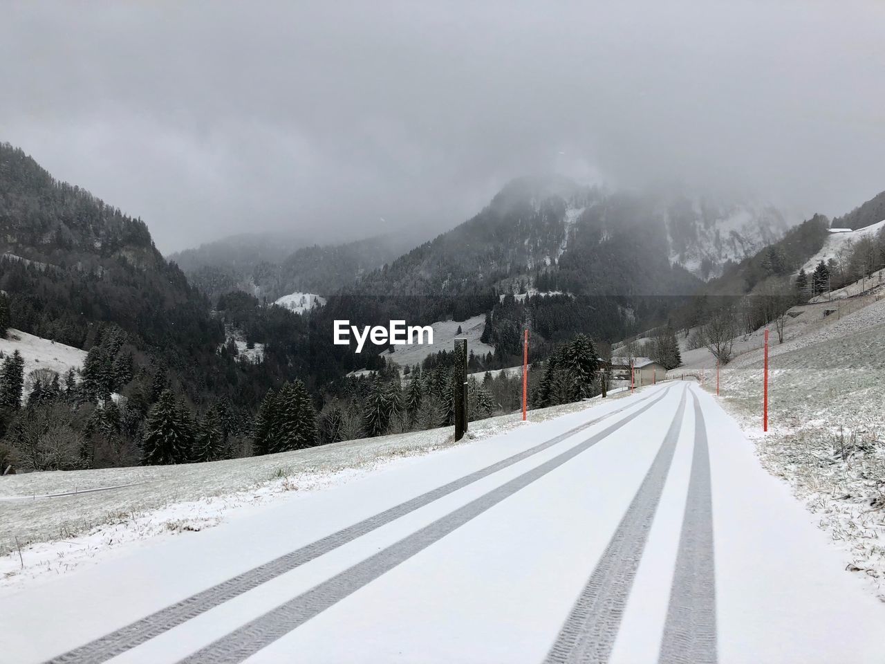 Road by snow covered mountains against sky