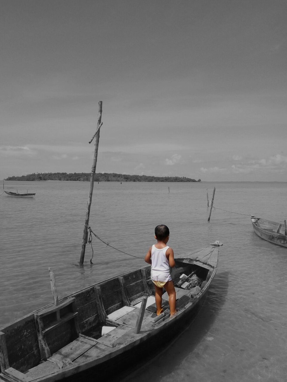 REAR VIEW OF MAN SITTING ON BOAT IN SEA