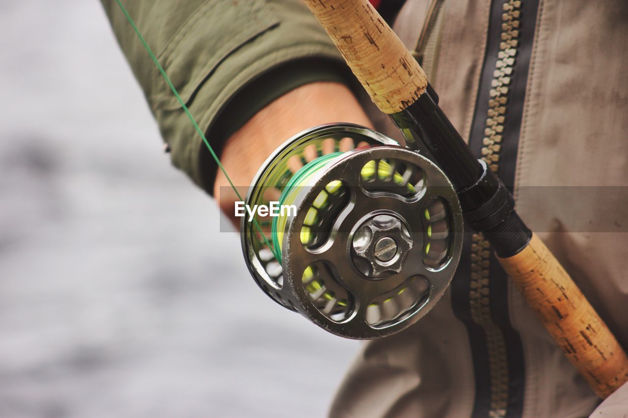 Midsection of man holding fishing rod