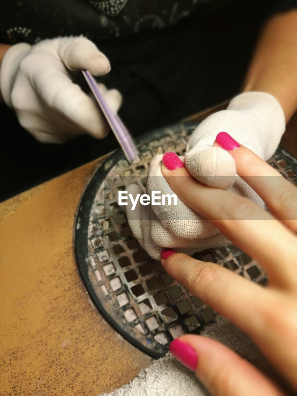 Midsection of woman doing manicure of customer
