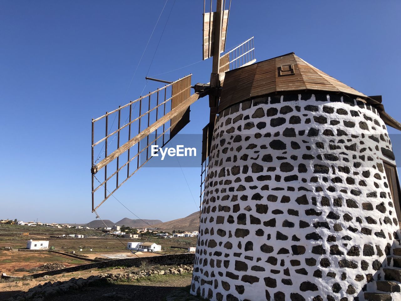 LOW ANGLE VIEW OF WINDMILL AGAINST CLEAR BLUE SKY