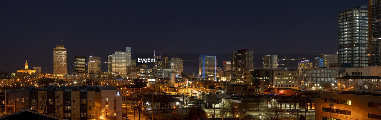 Illuminated buildings in city against sky at night