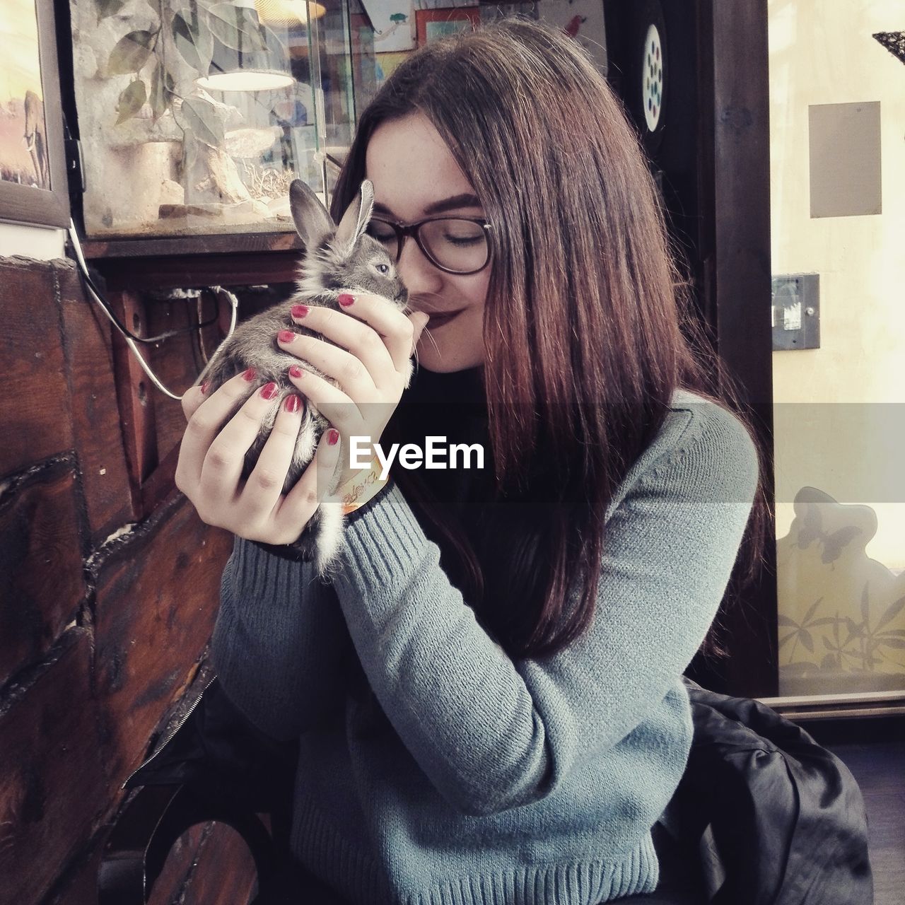 YOUNG WOMAN HOLDING CIGARETTE WHILE SITTING ON TABLE