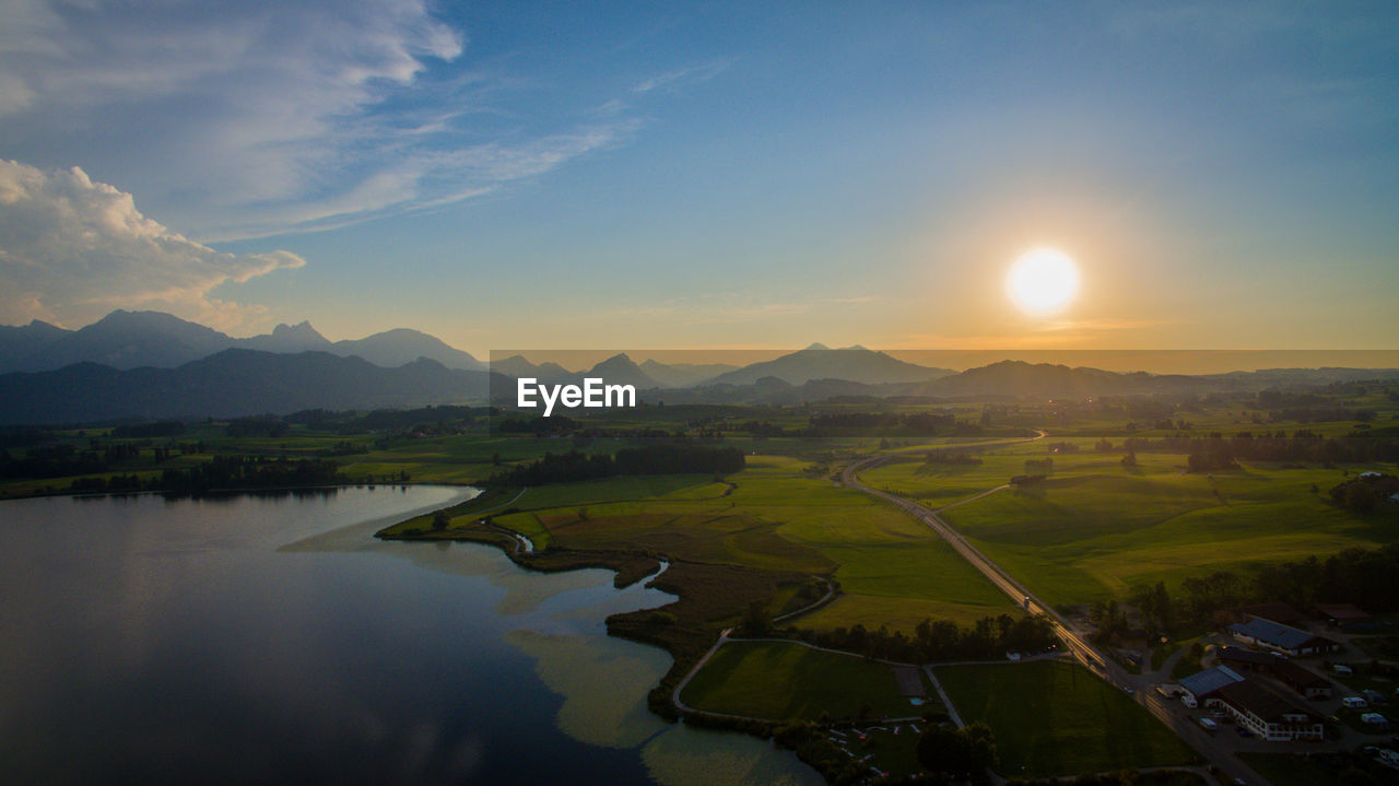 Scenic view of river and mountains against sky during sunset