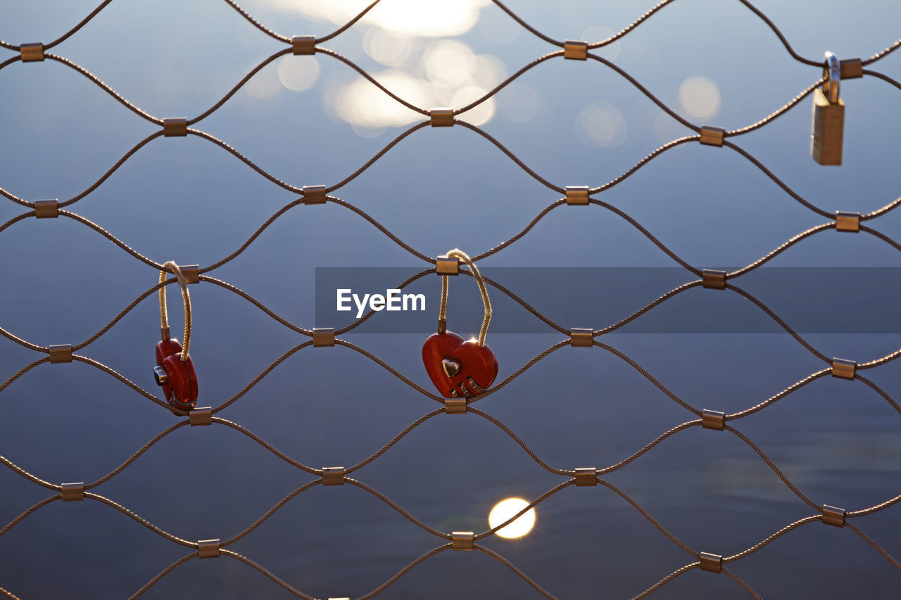 FULL FRAME SHOT OF CHAINLINK FENCE AGAINST SKY SEEN THROUGH METAL WIRE