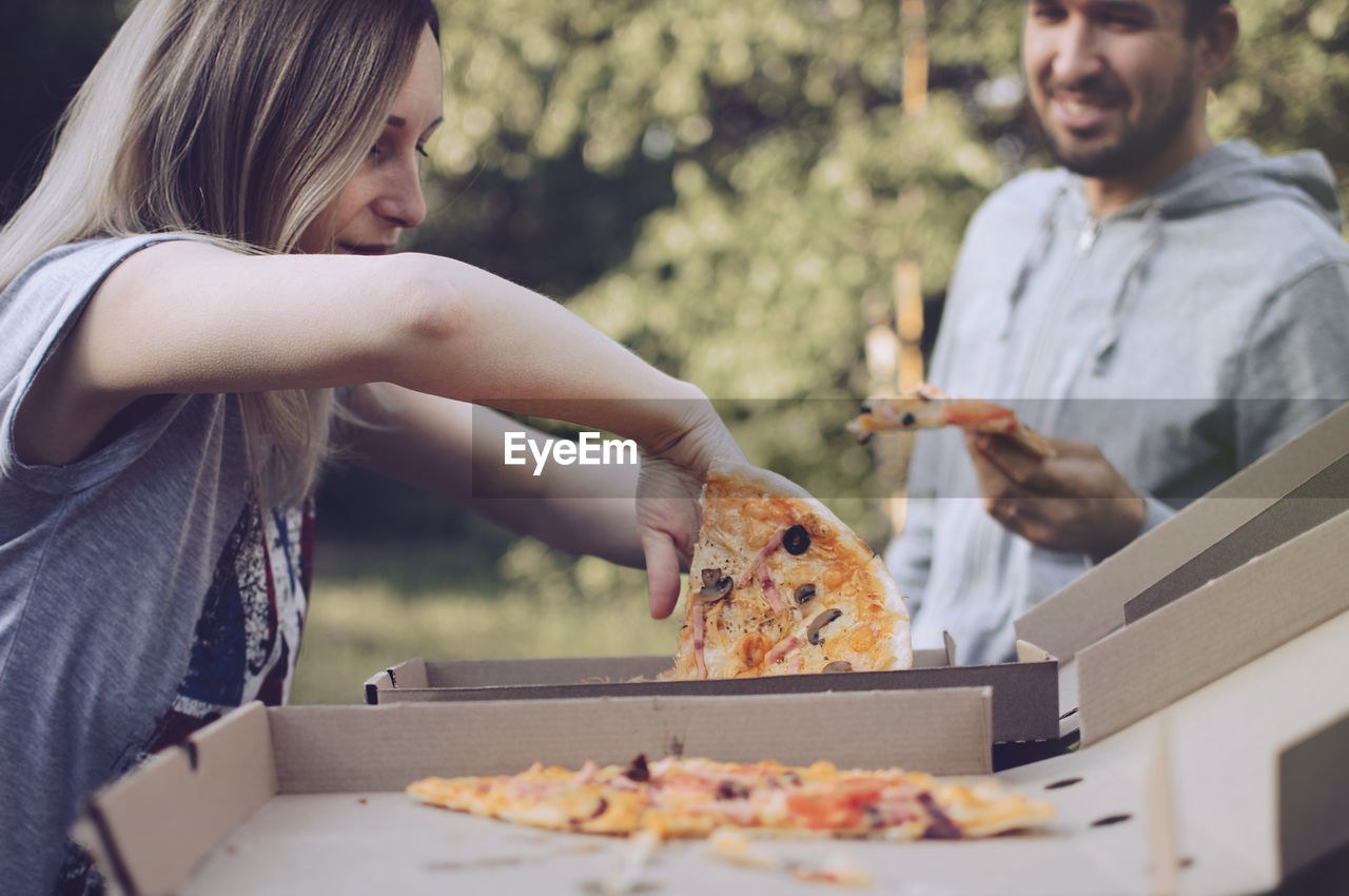 Young woman removing pizza from box
