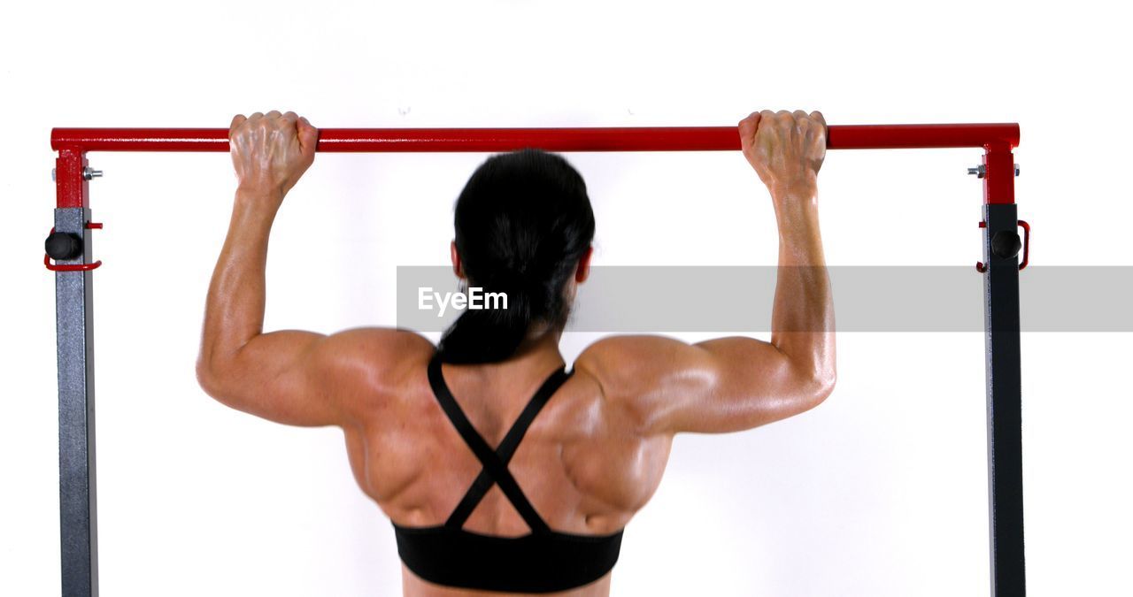 REAR VIEW OF WOMAN STANDING AGAINST WALL