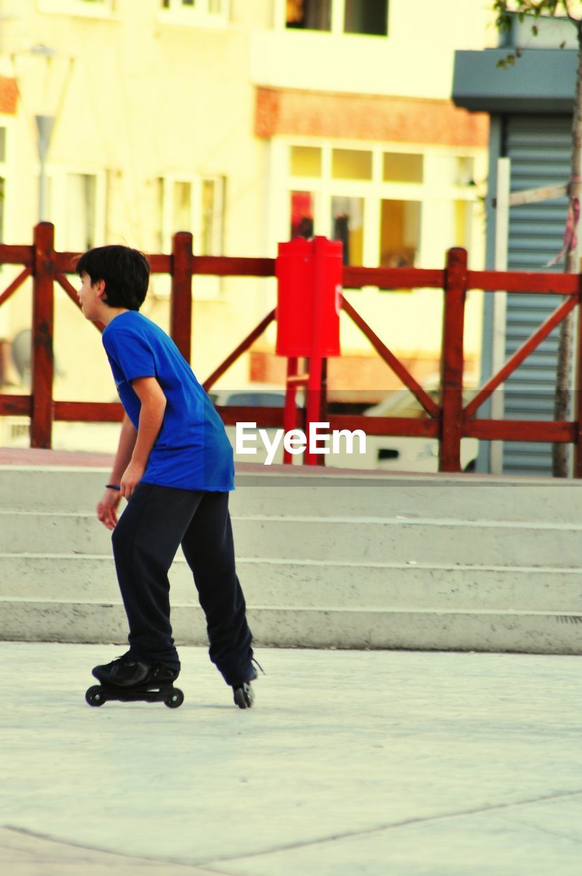 Full length side view of boy inline skating on street