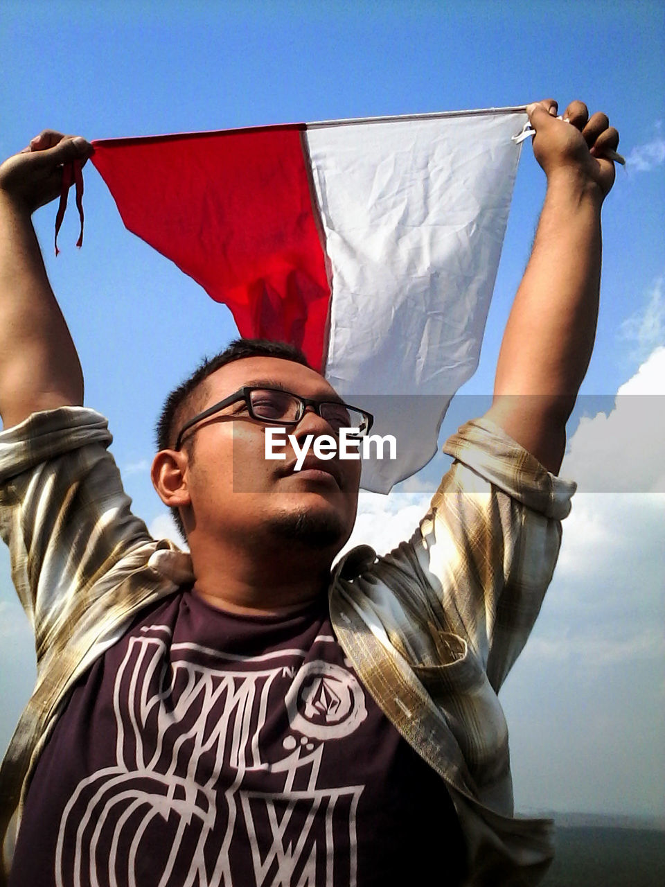 Low angle view of man with flag standing against sky