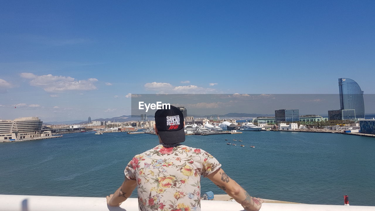 REAR VIEW OF MAN ON BEACH AGAINST SKY