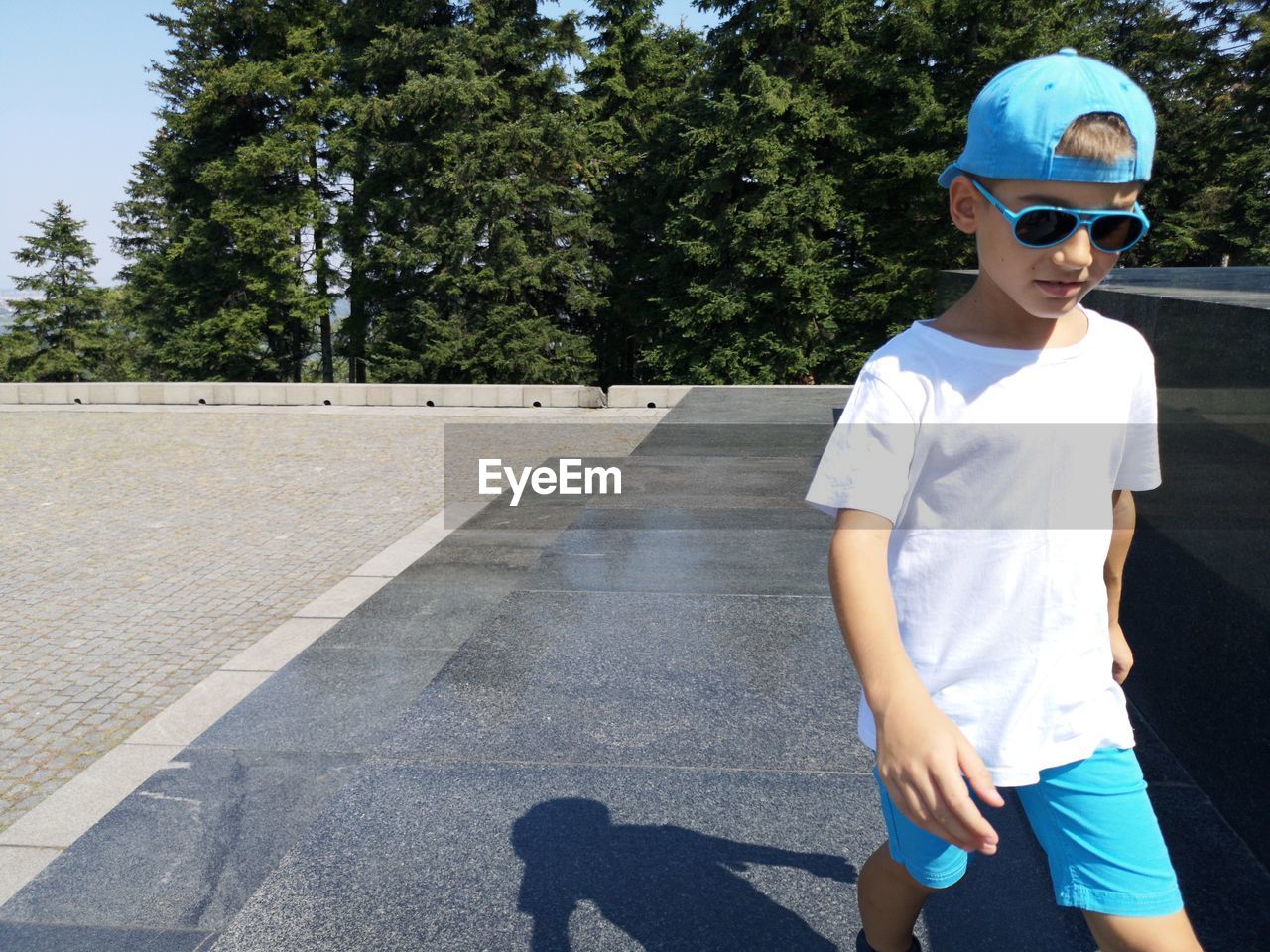 Cute boy walking on road during sunny day