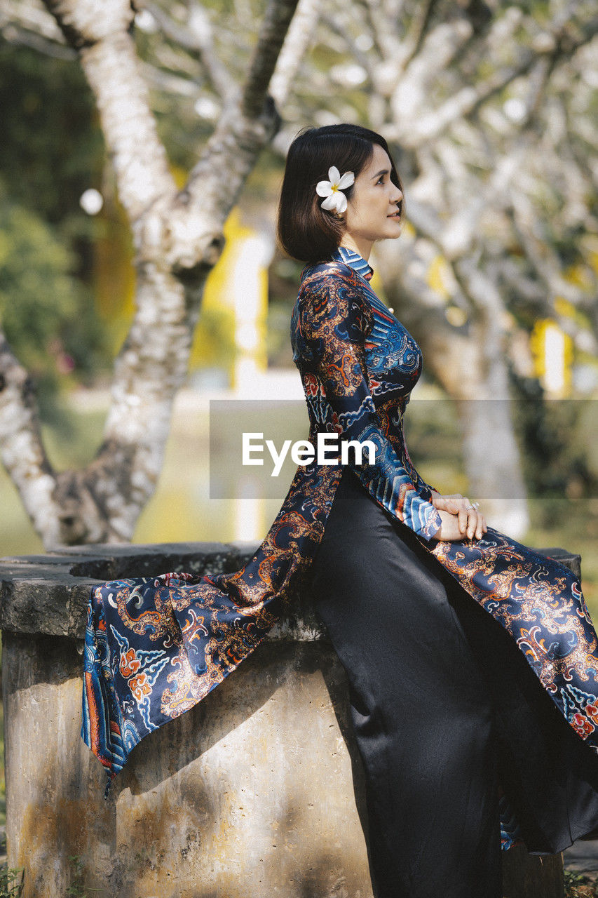 adult, women, fashion, one person, spring, clothing, young adult, nature, elegance, arts culture and entertainment, tree, dress, female, portrait, outdoors, plant, beauty in nature, lifestyles, traditional clothing, looking, forest, photo shoot, hairstyle, sitting, tradition, glamour, land, person, make-up, smiling