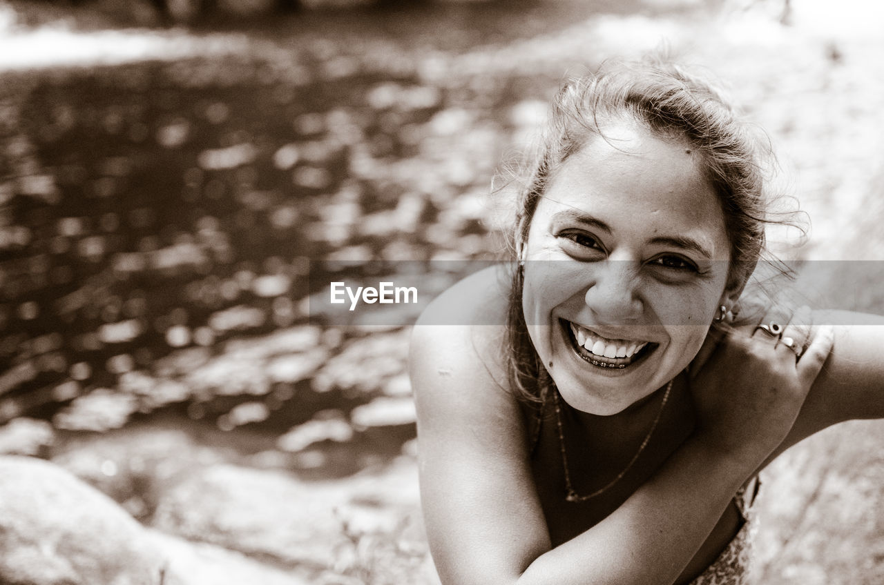 High angle portrait of smiling young woman against lake