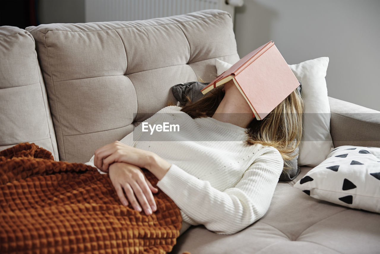 Woman sleeps on couch with book