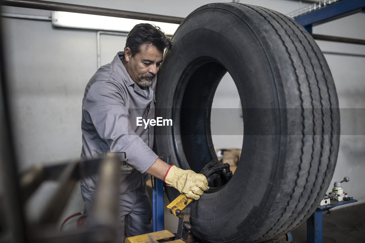 Tire repairer checking tire in factory