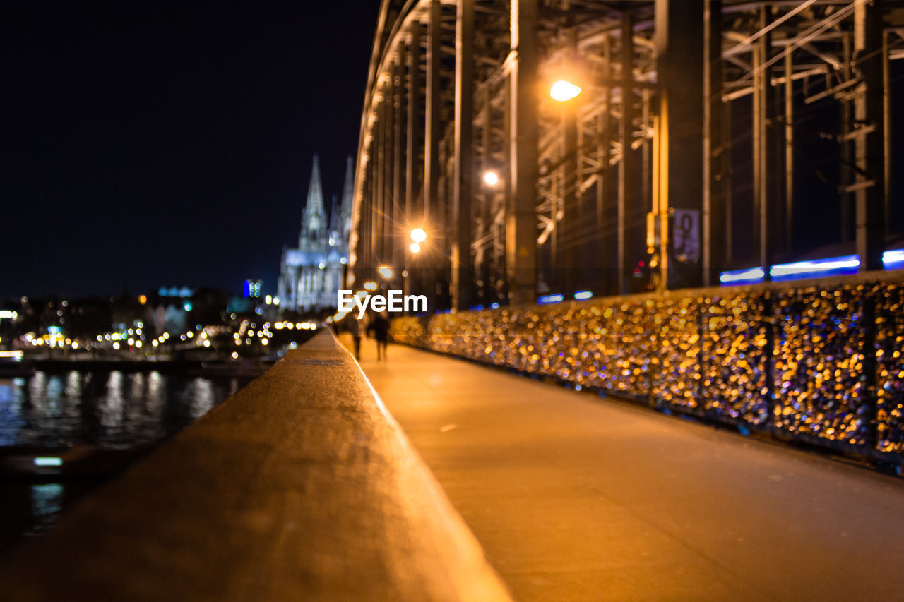 ILLUMINATED STREET LIGHTS BY RIVER AT NIGHT