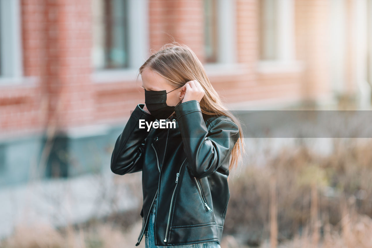 Girl wearing mask while standing outdoors