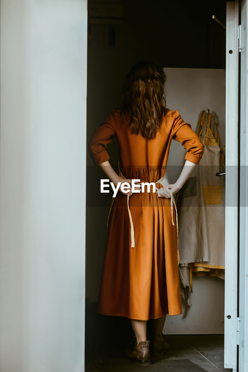 Woman standing at the front door tying an apron person