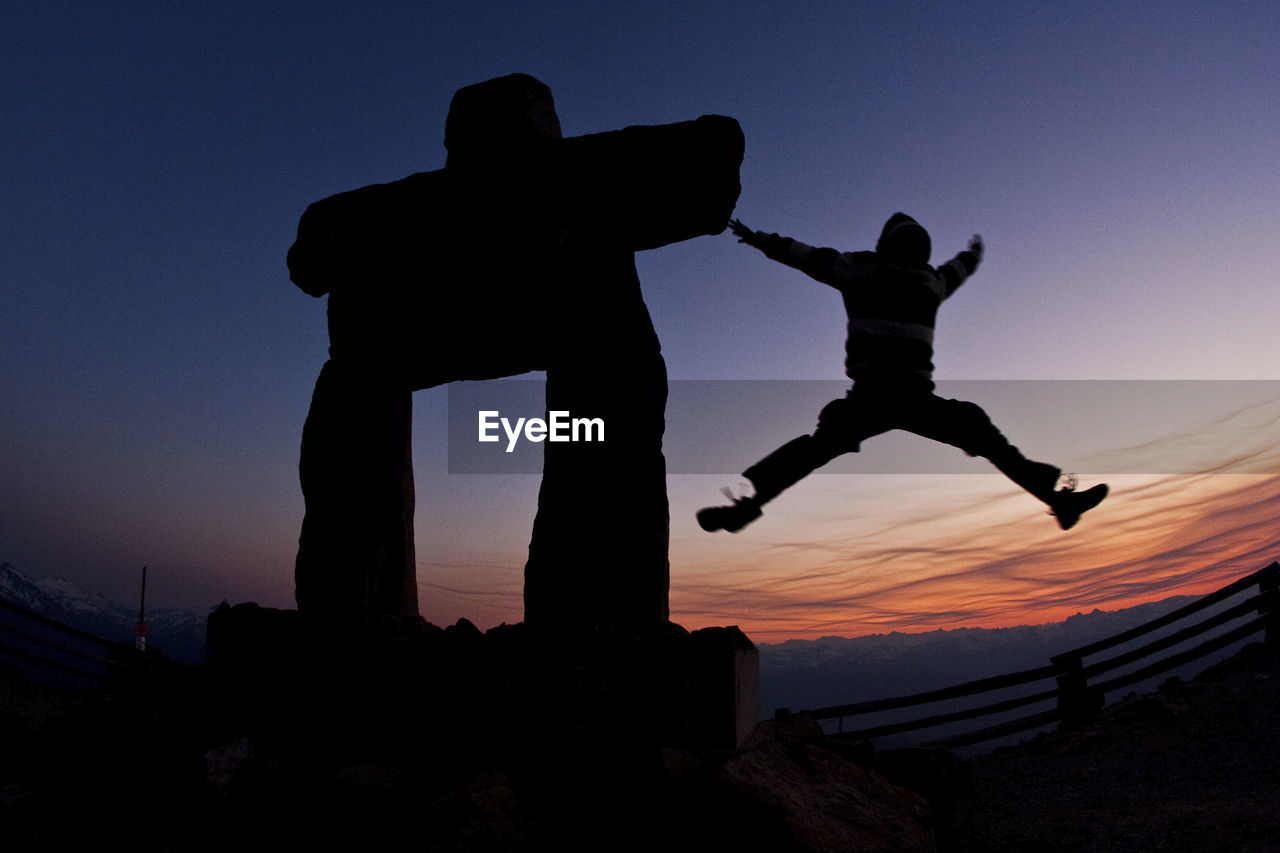 Silhouette man jumping against sky during sunset