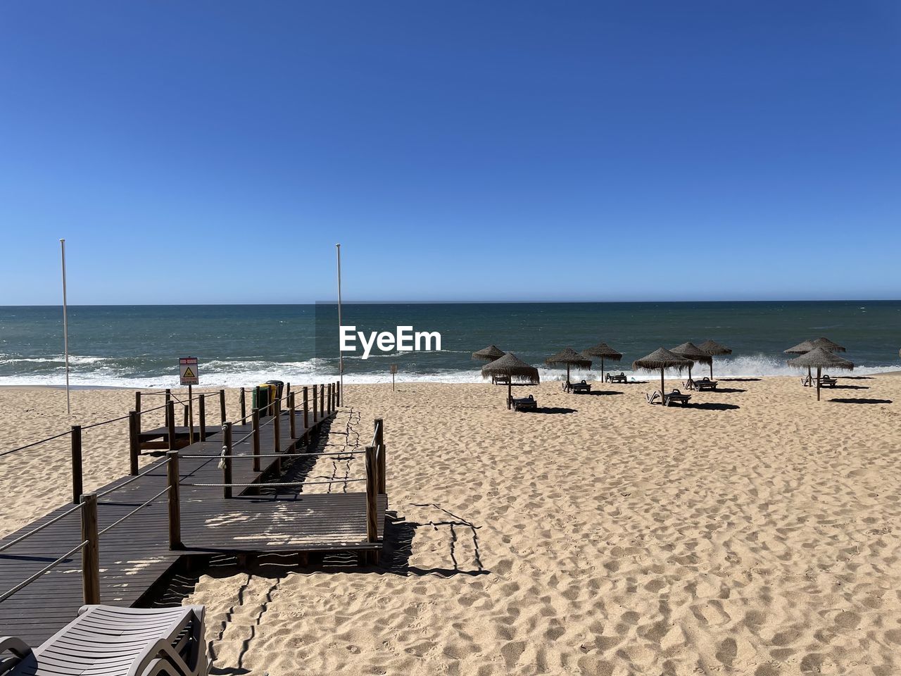 sea, beach, land, water, sky, body of water, sand, horizon over water, shore, horizon, nature, clear sky, ocean, scenics - nature, beauty in nature, chair, coast, vacation, sunny, blue, sunlight, tranquility, tranquil scene, holiday, day, seat, trip, summer, travel destinations, copy space, travel, bay, walkway, outdoors, no people, relaxation, idyllic, tourism, coastline, non-urban scene, seascape, urban skyline