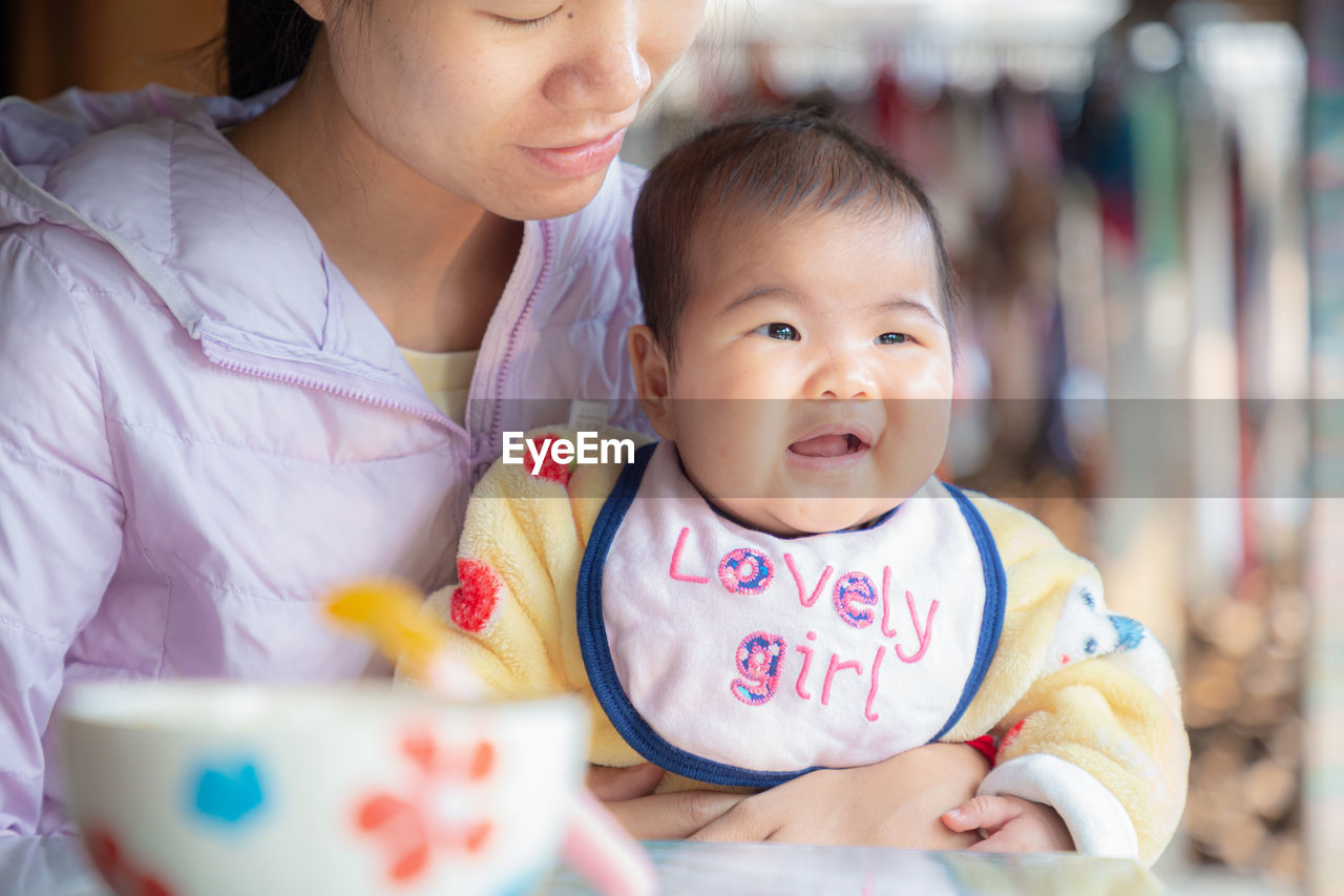 Close-up of mother holding daughter with text on dress