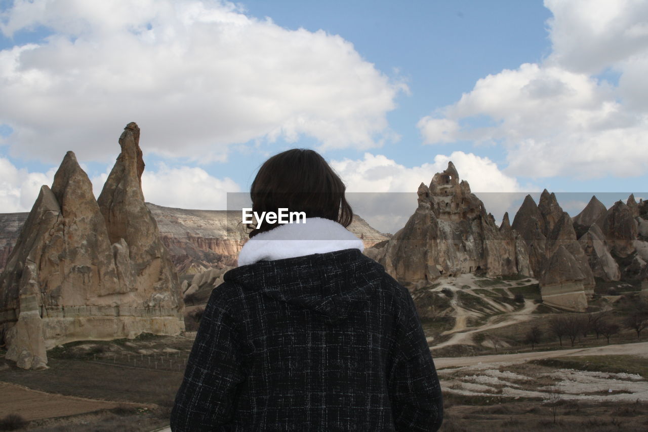 Rear view of man looking at mountain range against cloudy sky