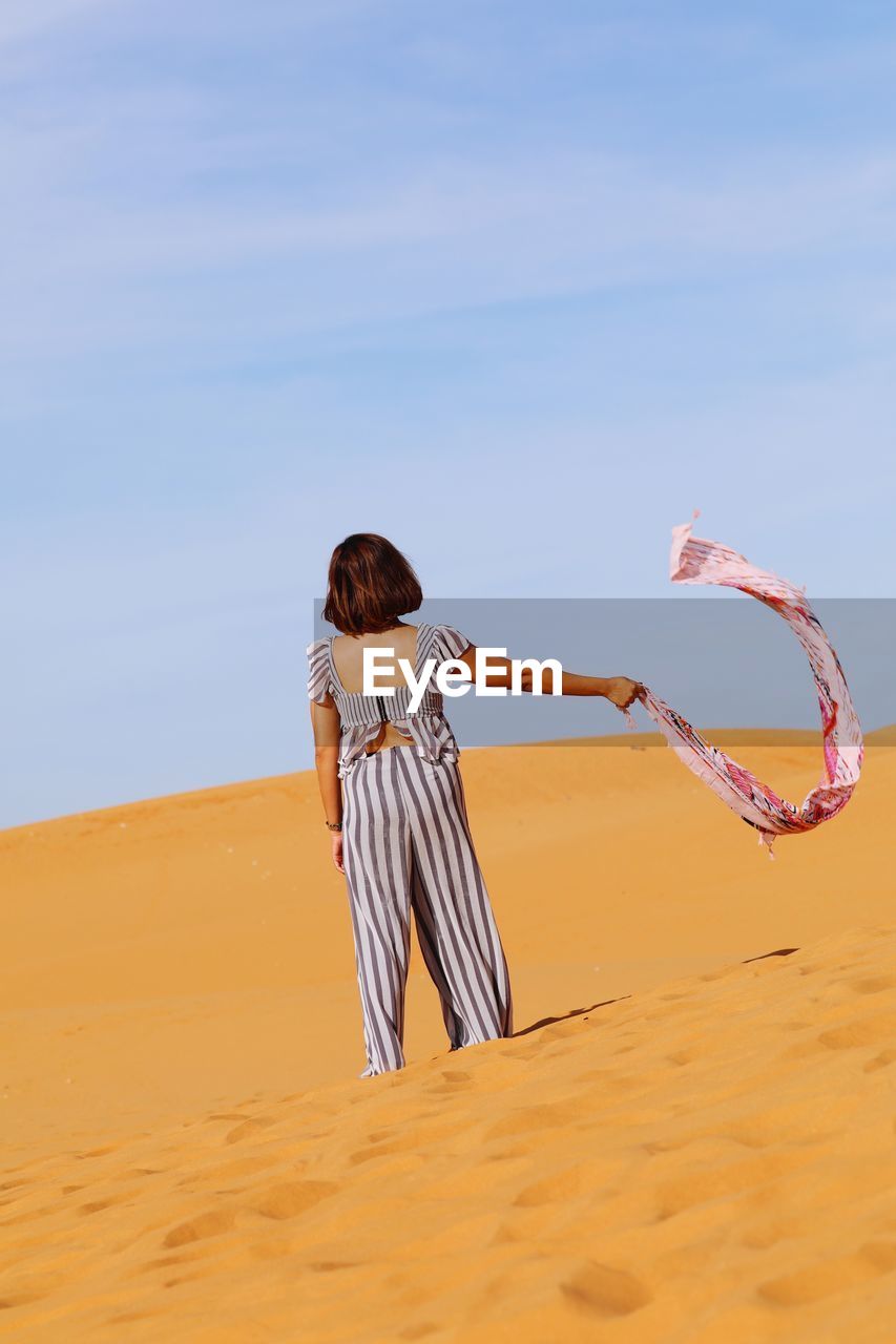 REAR VIEW OF WOMAN WITH UMBRELLA ON BEACH