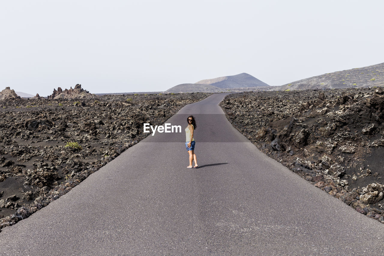 Woman standing on road against clear sky