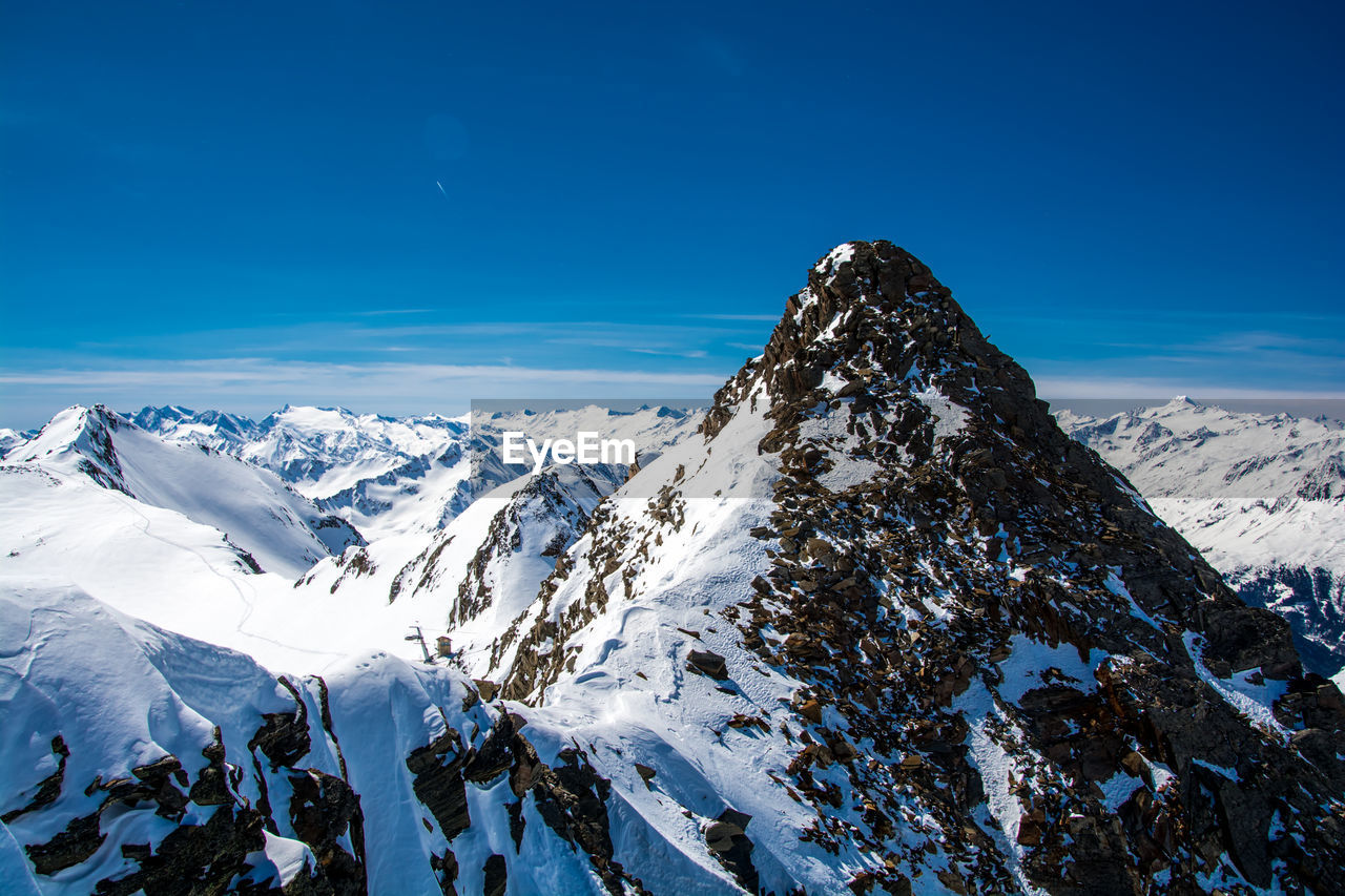 Scenic view of snowcapped mountains against blue sky