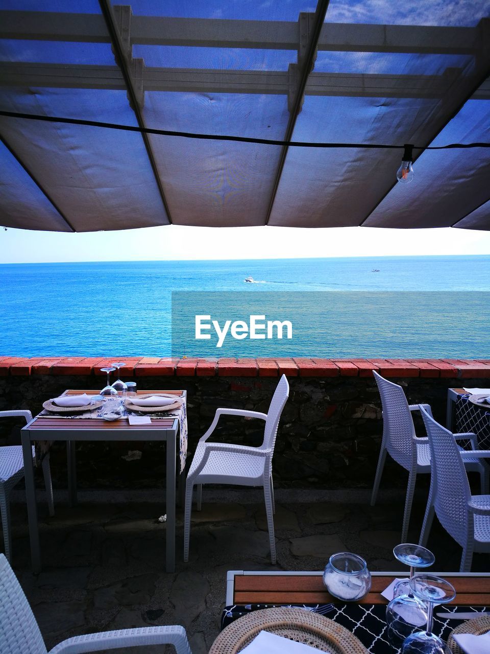 EMPTY CHAIRS AND TABLE AT BEACH AGAINST SKY