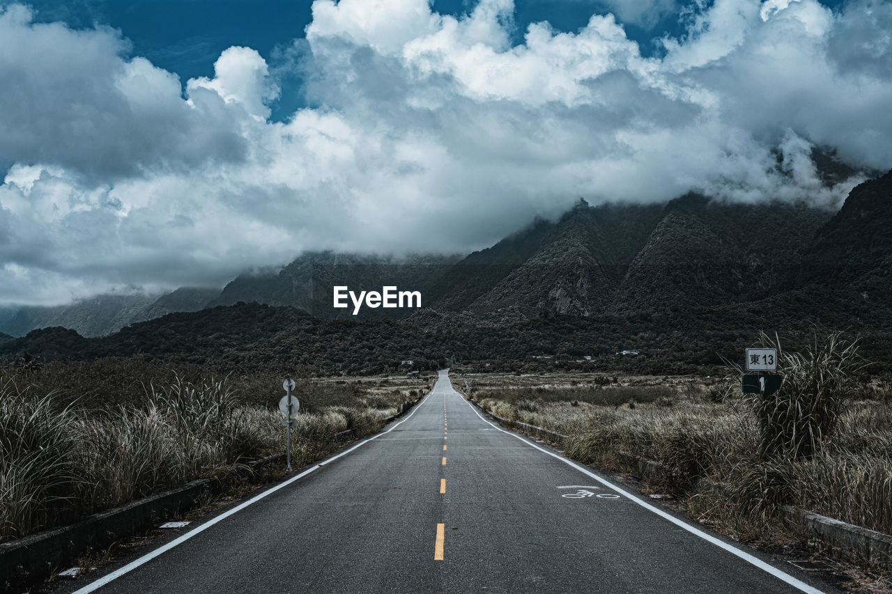 Road leading towards mountains against sky