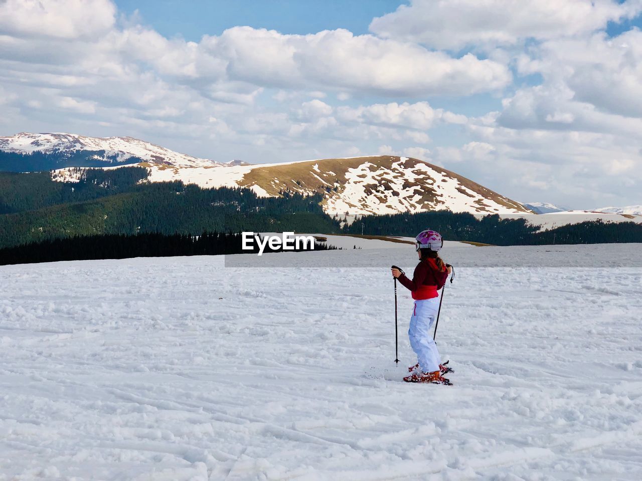 Woman on skiing on snow covered field against sky