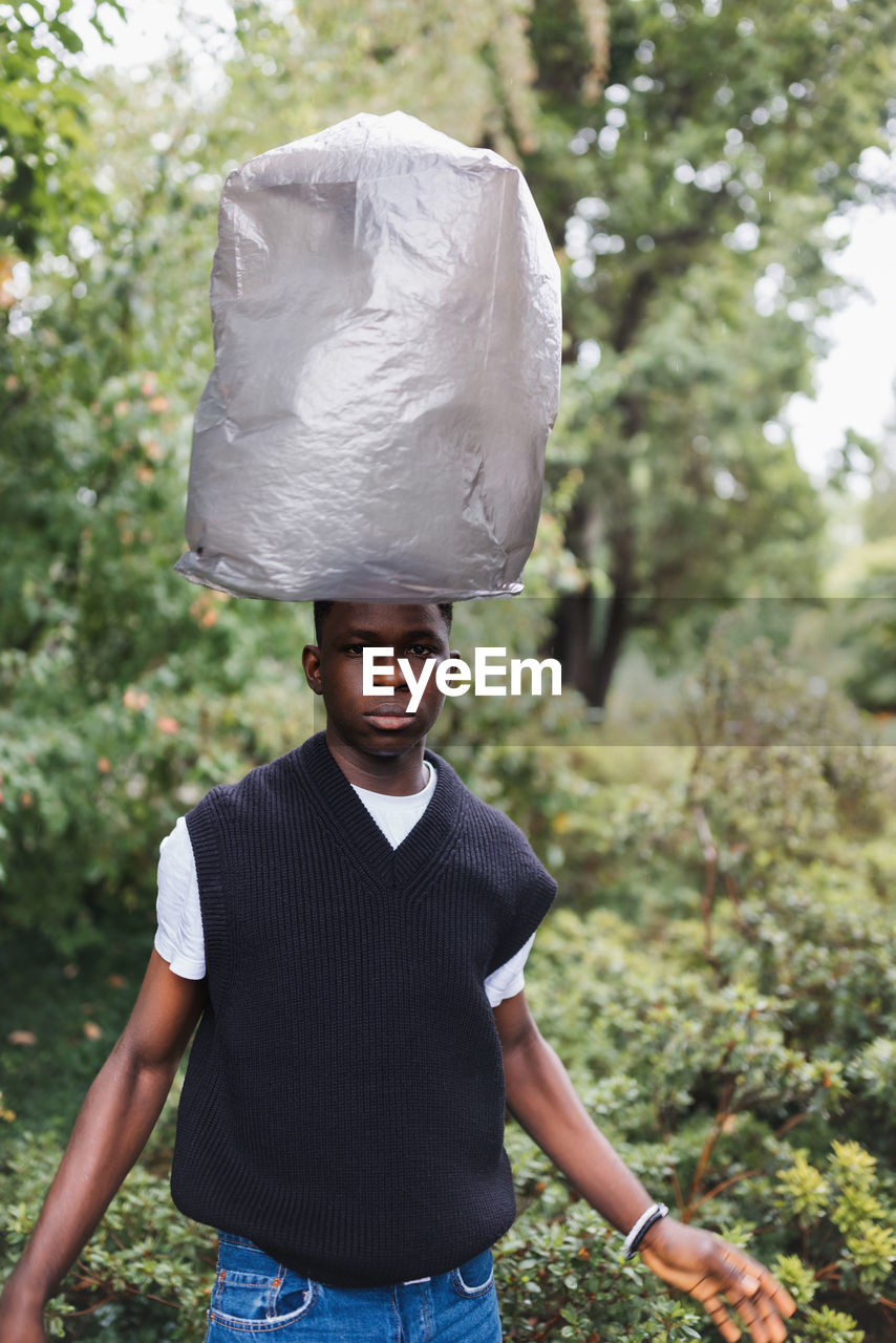 Young african man with plastic over head. plastic pollution concept