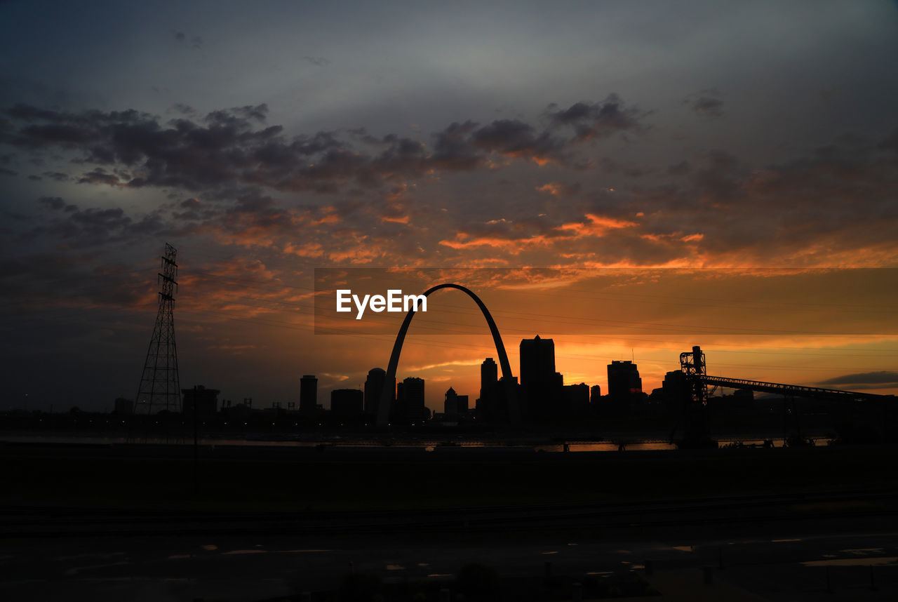 Silhouette of buildings against cloudy sky during sunset