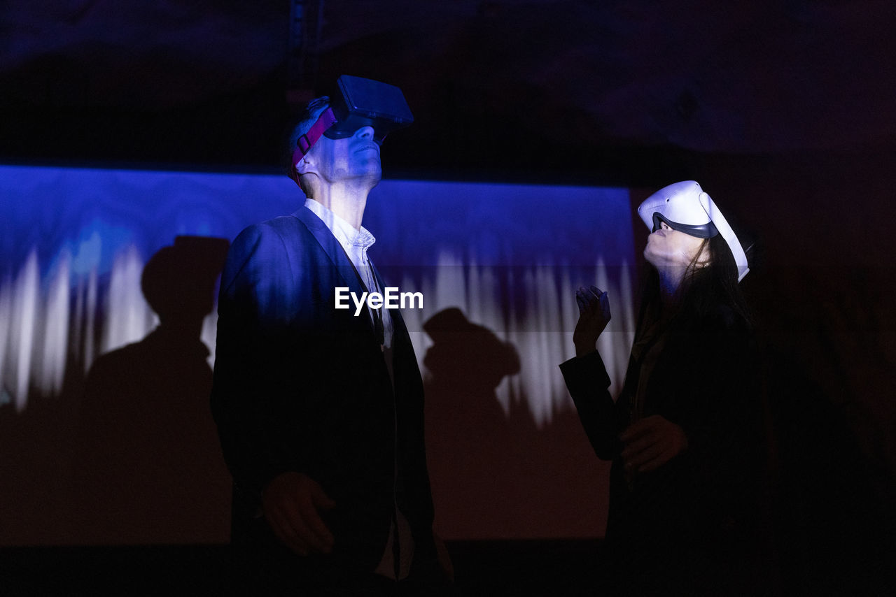 Multiracial female and male colleagues watching through futuristic glasses in workshop