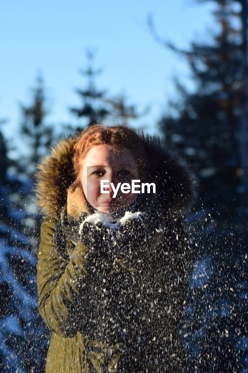 Portrait of woman playing with snow