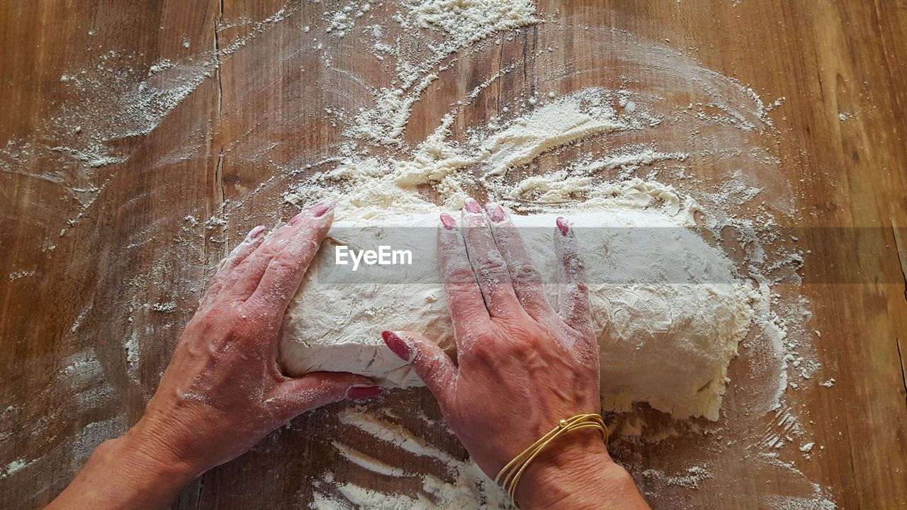 Cropped hands of woman kneading dough on table