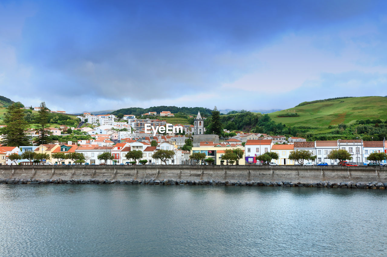 HOUSES BY RIVER AGAINST SKY